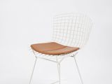 une photo d'une chaise en fil métallique blanche avec un coussin d'assise marron