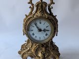 a gold clock sitting on a white surface with a key