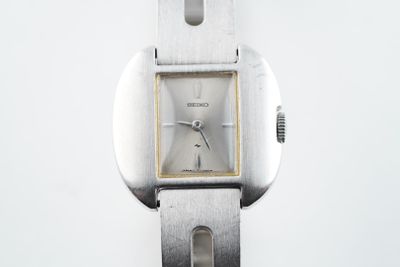 gros plan d'une montre en argent sur une surface blanche