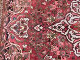 an antique persian rug with a red background and a floral design
