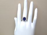 une main sur laquelle est passée une bague sertie d'une pierre bleue