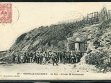 une vieille photo montrant un groupe d'hommes debout devant une montagne