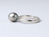 a close up of a ring with a pearl on a white surface