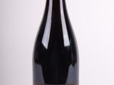 the bottle of wine is sitting on the table on a white surface