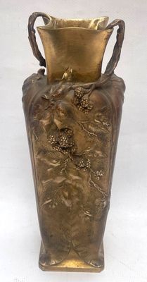a bronze vase that is sitting on a white surface