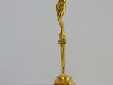 a gold statue of a person on a cross on a pedestal