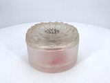 a glass container with a pink substance on a white table
