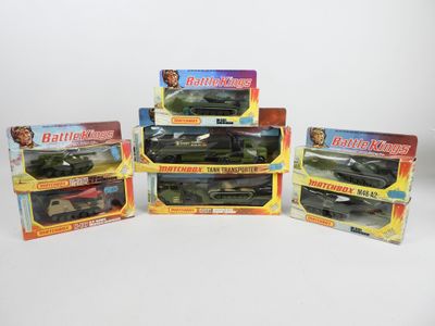 six jouets représentant des véhicules militaires, emballés dans des boîtes, posés sur une surface blanche