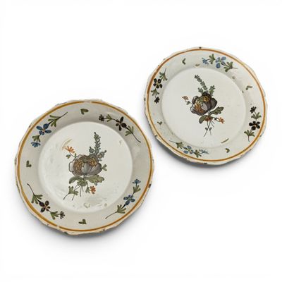 two plates with flowers on them on a white surface