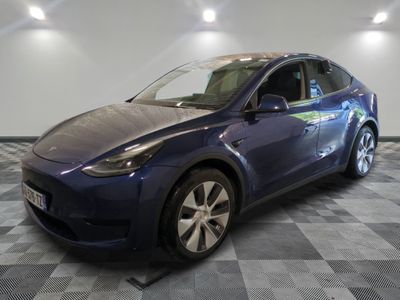 a blue tesla model y parked on a checkered tile floor