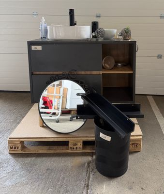 une poubelle noire posée sur une palette à côté d'un miroir
