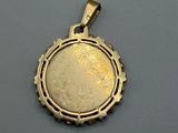 a close up of a gold pendant on a gray surface