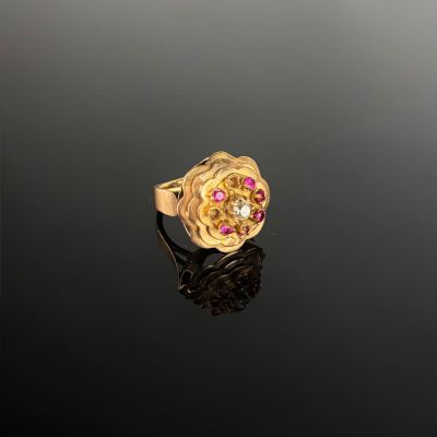 a close up of a gold ring with pink stones on a black surface