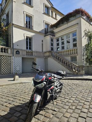une moto garée devant une maison, dans une rue pavée