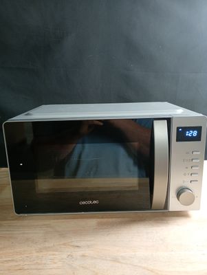 Quelqu'un prend une photo d'un micro-ondes posé sur une table en bois.