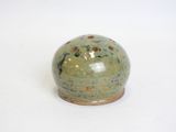 a small green vase with holes in it on a white surface