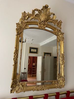 a gold mirror hanging on the wall above a red curtain