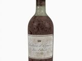 une vieille bouteille de vin posée sur une surface blanche