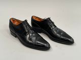 men ' s black dress shoes on a white surface