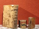 trois livres posés sur une table, avec un mur rouge en arrière-plan