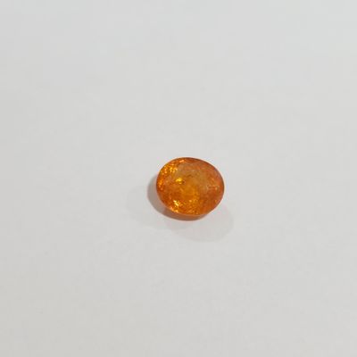 a close up of an orange sapphire stone on a white surface