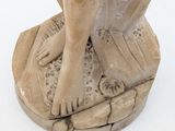 a statue of a woman sitting on top of a rock