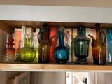 de nombreux vases en verre de différentes couleurs posés sur une étagère