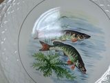 two plates with fish painted on them sitting on a table