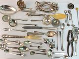 beaucoup d'argenterie sur une table, avec des cuillères et des couteaux-cuillères