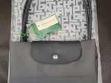 un sac à main gris muni d'une poignée noire et d'une étiquette verte
