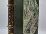 un vieux livre à la couverture verte posé sur une table blanche