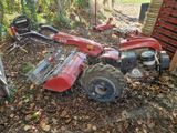 un petit tracteur rouge garé dans les bois