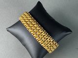a close up of a black pillow with a gold bracelet on it