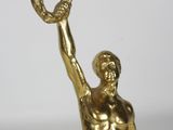 gold statue of a man holding a doughnut in his right hand
