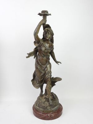 bronze statue of a woman holding a bird on her head