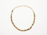 un collier en or orné de perles noires et blanches sur fond blanc
