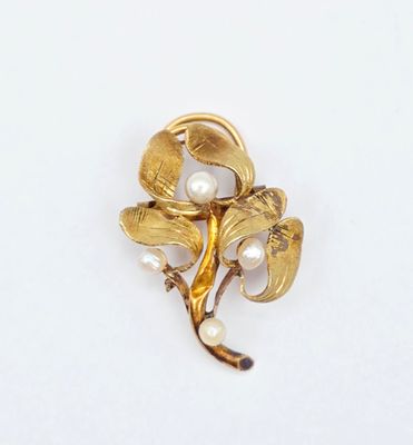 un gros plan d'une broche en forme de fleur ornée de perles sur un fond blanc