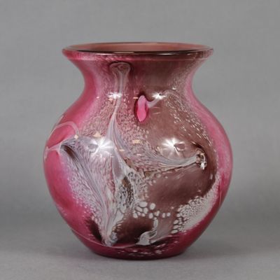 a pink vase with a bird on it on a gray surface