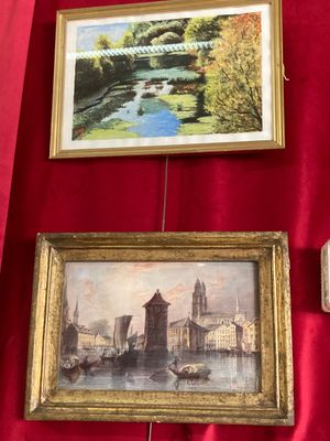 deux tableaux encadrés représentant une rivière et un pont, accrochés à un mur rouge