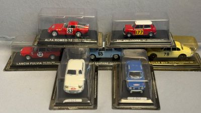 six modèles réduits de voitures différents sont exposés dans une vitrine posée sur une table