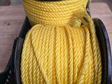 une corde torsadée jaune dans un panier posé sur une table, à côté d'une paire de ciseaux