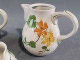 two small vases with orange flowers painted on them sitting on a table
