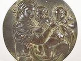 une image représentant une plaque en bronze sur laquelle figure une femme tenant un enfant dans ses bras