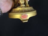 a person holding a gold trophy with a horse on it
