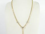 a gold necklace with a cross pendant and a chain on a mannequin
