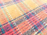 un gros plan sur un tapis à carreaux multicolores posé sur un parquet