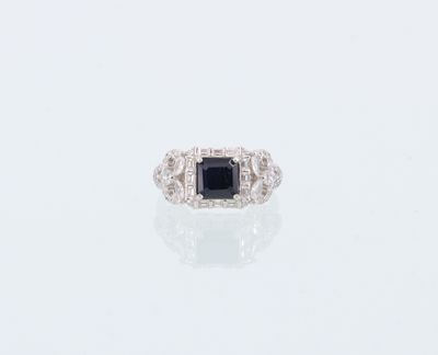 une bague en diamant noir et blanc posée sur une surface blanche