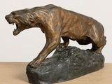 bronze statue of a lion on a rock with its mouth open