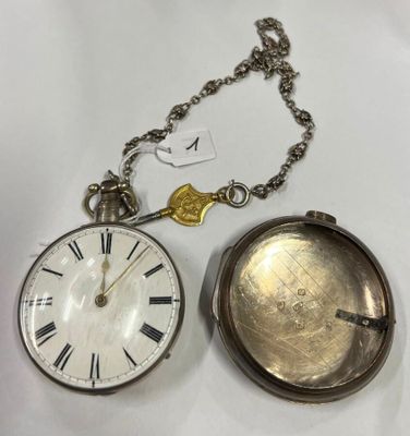 une montre de poche en argent posée à côté d'une chaîne à laquelle est accrochée une clé