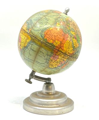un petit globe posé sur un socle, sur une surface blanche